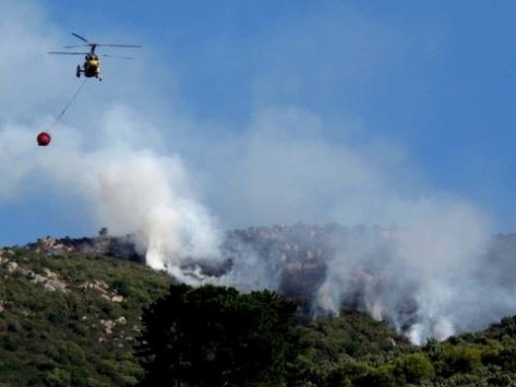 A helicopter water bombs a bush fire on the Cape Flats.